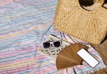 Vasaros atostogų krepšys: 10 daiktų, be kurių neverta keliauti prie jūros Paplūdimio atostogos su visa reikalinga įranga – rankšluosčiai, krepšys, kremas nuo saulės ir akiniai tvarkingai sudėti ant smėlio.