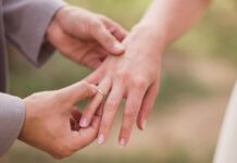 Vestuviniai žiedai iš savo aukso: kiek sutaupote realiai? Žiedai iš savo aukso – jaunikis per ceremoniją užmauna auksinį vestuvinį žiedą nuotakai ant rankos.