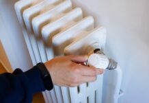 Kaip sutaupyti šildymo sezono metu nepakenkiant komfortui Kaip sutaupyti šildymo sezono metu. Žmogus reguliuoja radiatoriaus šilumą.