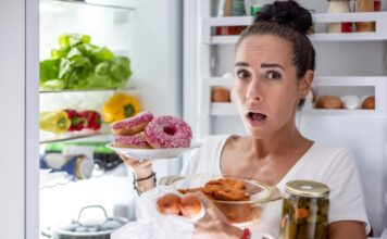 Nuolatinis alkis: kodėl vis norisi valgyti net pavalgius? Nuolatis alkis. Moteris rausiasi po šaldytuvą.