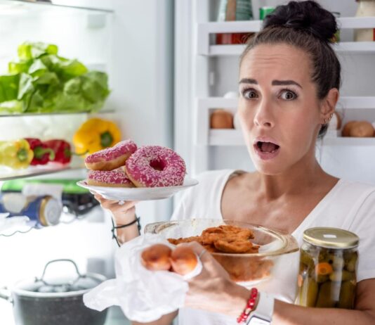 Nuolatinis alkis: kodėl vis norisi valgyti net pavalgius? Nuolatis alkis. Moteris rausiasi po šaldytuvą.